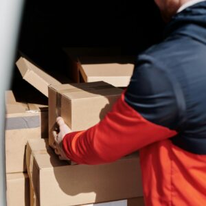 A delivery worker efficiently loads cardboard boxes into a vehicle for shipment.