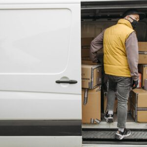 A deliveryman unloading packages from a van, showcasing modern logistics.